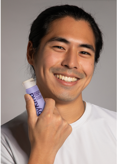 Man holding a purple bottle with a gray background
